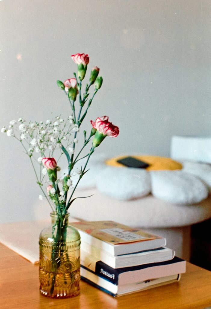 Flores en un jarrón junto a una pila de libros