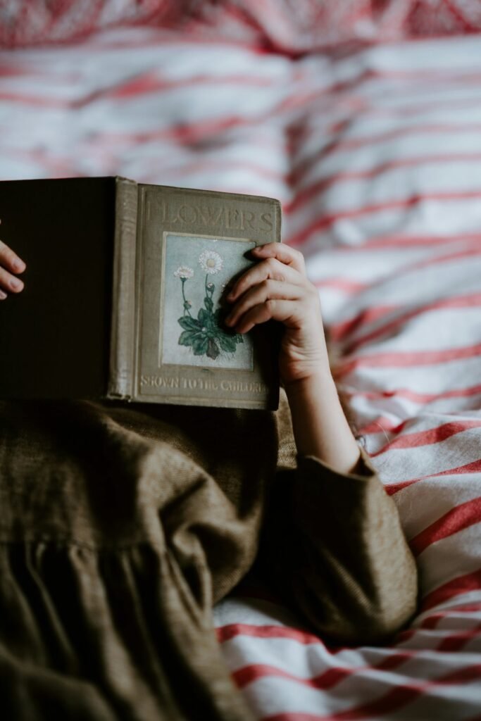 Mujer tumbada que lee un libro con una flor en la cubierta