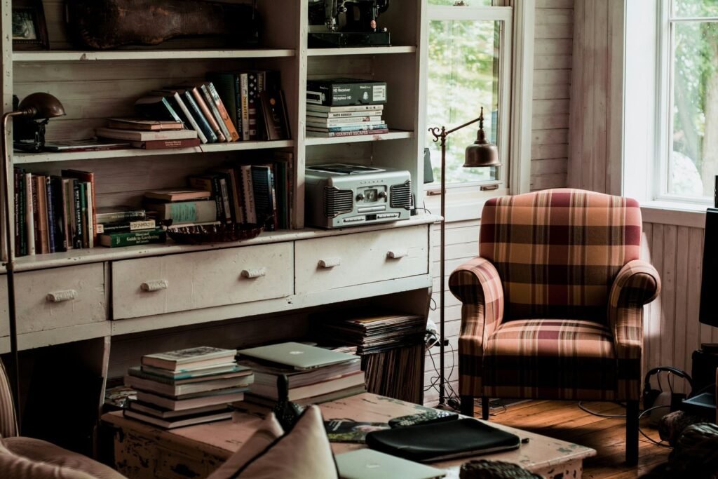 Rincón de lectura con estantería, sillón de cuadros y libros