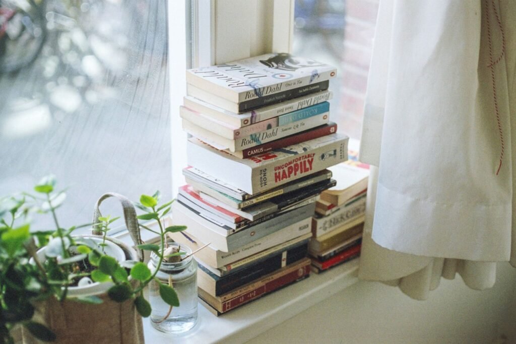 Pila de libros junto a una ventana luminosa